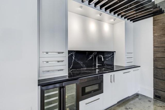 kitchen featuring beverage cooler, tasteful backsplash, white cabinets, built in microwave, and a sink