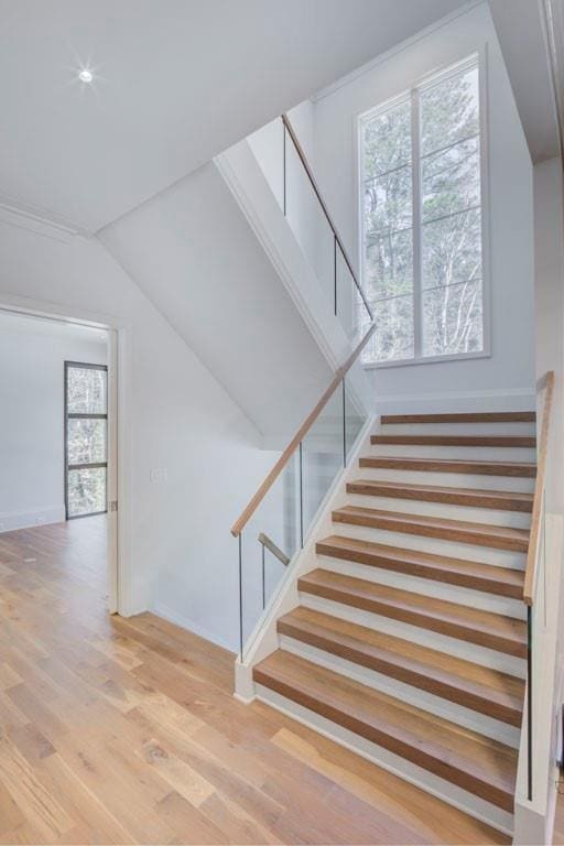 stairs with baseboards, wood finished floors, and lofted ceiling