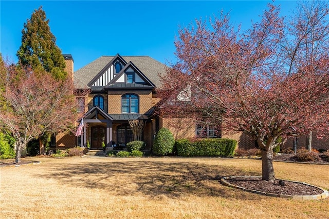 view of front of home featuring a front lawn, a chimney, and brick siding