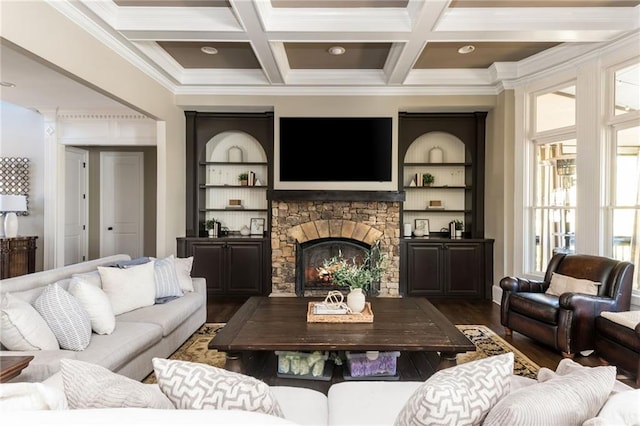 living area featuring beam ceiling, ornamental molding, a stone fireplace, wood finished floors, and coffered ceiling