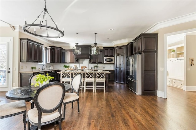 kitchen with dark brown cabinetry, a center island, hanging light fixtures, stainless steel appliances, and light countertops