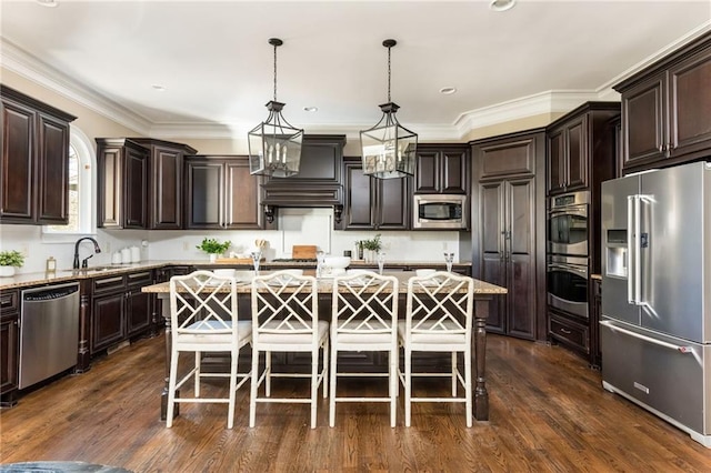 kitchen featuring dark brown cabinetry, a kitchen island, a kitchen breakfast bar, stainless steel appliances, and a sink