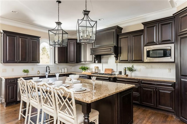 kitchen featuring appliances with stainless steel finishes, a kitchen bar, dark brown cabinetry, and a center island