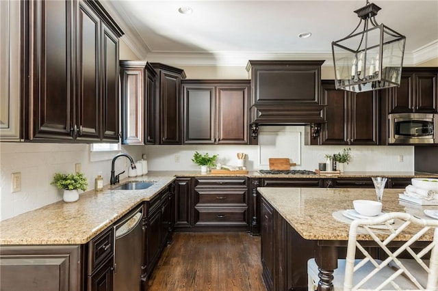 kitchen featuring dark wood-style flooring, decorative light fixtures, appliances with stainless steel finishes, ornamental molding, and a sink