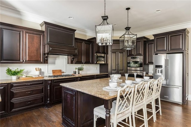 kitchen featuring stainless steel appliances, a center island, decorative light fixtures, and dark brown cabinetry