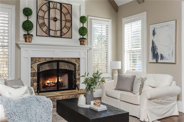 sitting room with vaulted ceiling and a stone fireplace