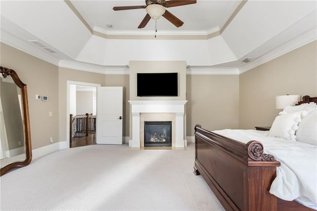 bedroom featuring baseboards, a raised ceiling, light colored carpet, a fireplace with flush hearth, and ornamental molding