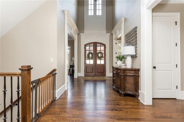 entryway with arched walkways, french doors, a towering ceiling, dark wood-type flooring, and baseboards