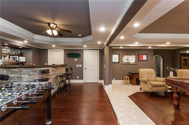 rec room with arched walkways, recessed lighting, ornamental molding, a dry bar, and a raised ceiling