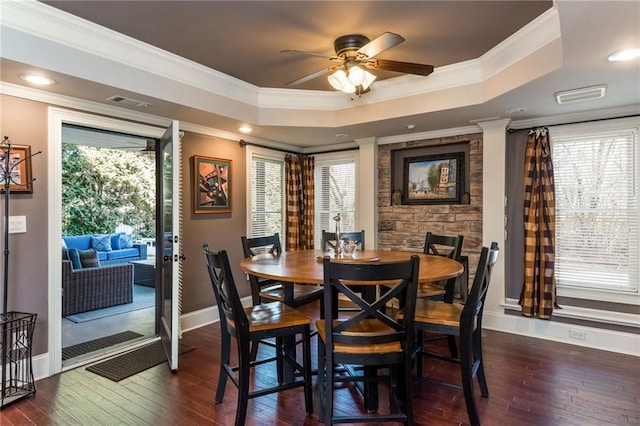 dining room with dark wood-style floors, a tray ceiling, visible vents, and crown molding