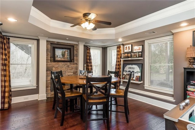 dining room with dark wood-style floors, a tray ceiling, and crown molding