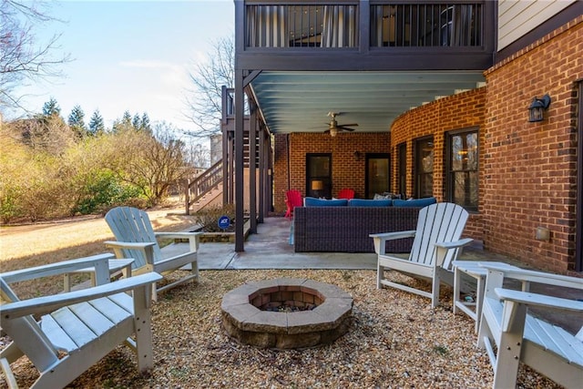 view of patio featuring ceiling fan, stairway, and an outdoor living space with a fire pit