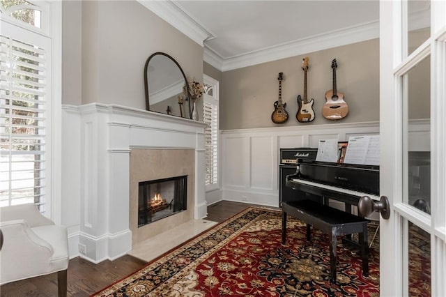 living area with a wealth of natural light, dark wood-style floors, a decorative wall, and crown molding