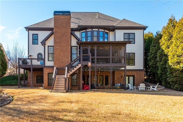 rear view of house with brick siding, a chimney, a lawn, a sunroom, and stairs