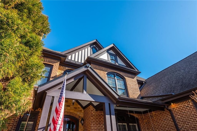 exterior space with brick siding and a shingled roof