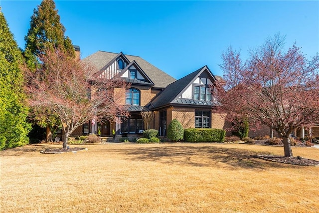 view of front of property featuring a standing seam roof, brick siding, metal roof, and a front lawn