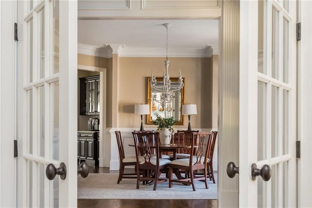 dining room with a chandelier, french doors, wood finished floors, and crown molding