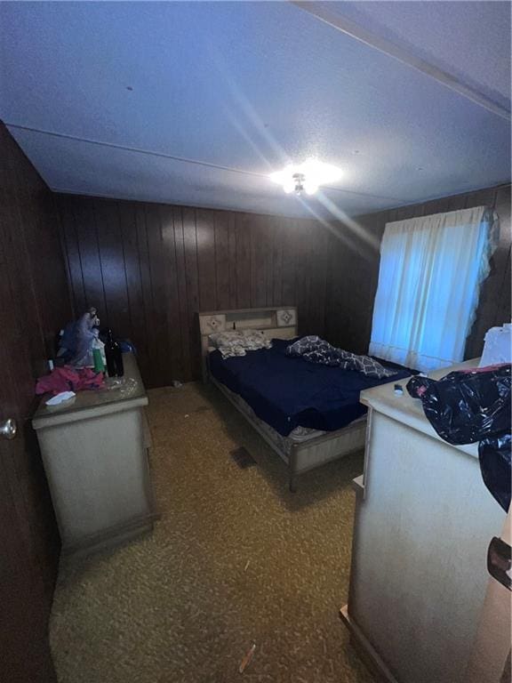 carpeted bedroom featuring wood walls