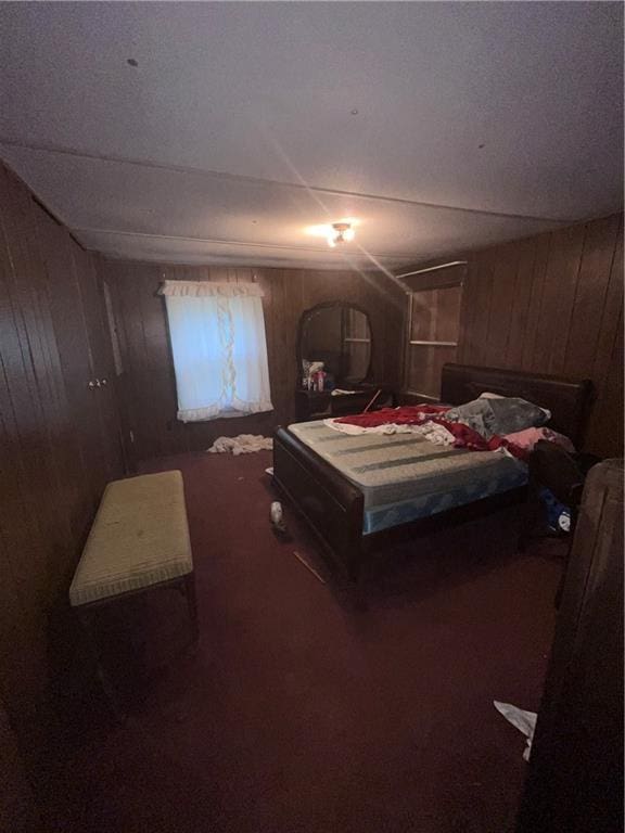 bedroom with dark carpet and wood walls