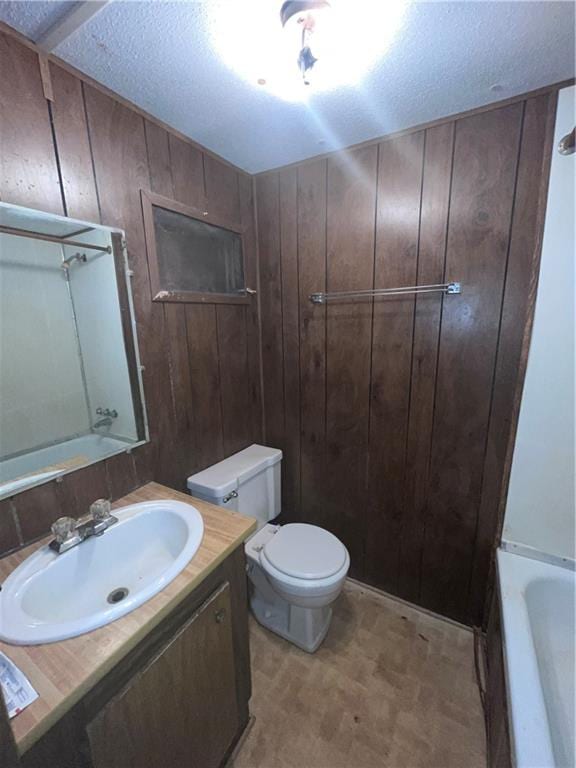 full bathroom featuring a textured ceiling, wood walls, shower / bath combination, vanity, and toilet