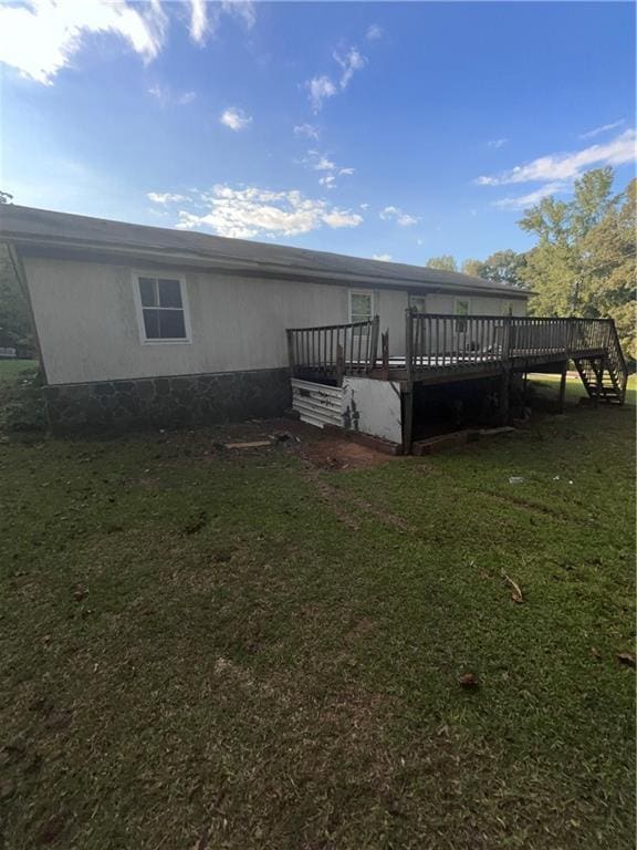 back of house with a wooden deck and a lawn