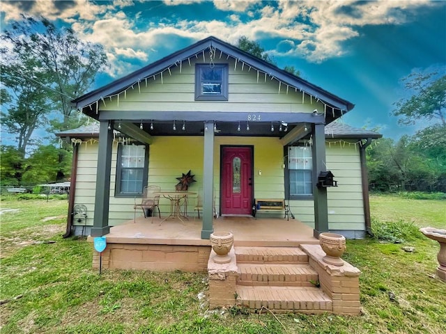 bungalow-style home with a front yard and covered porch