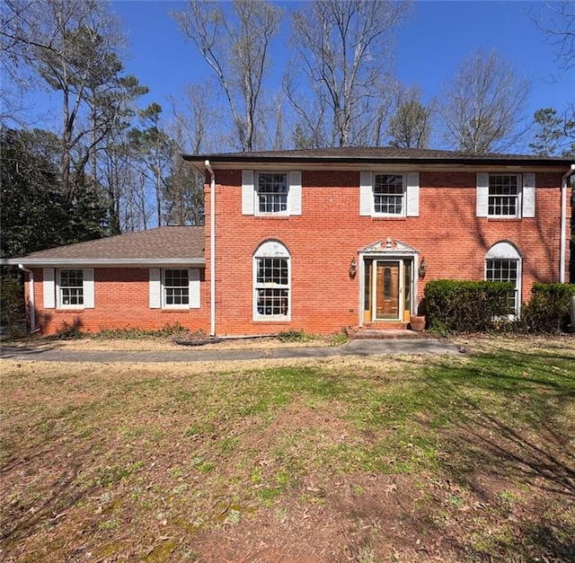 colonial-style house with brick siding and a front yard