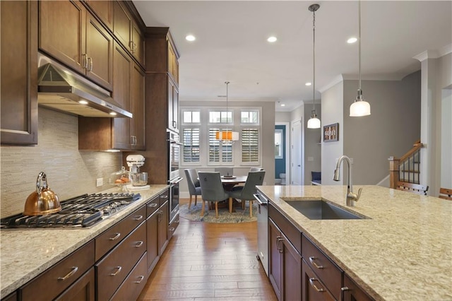 kitchen featuring stainless steel appliances, light stone countertops, ornamental molding, pendant lighting, and sink