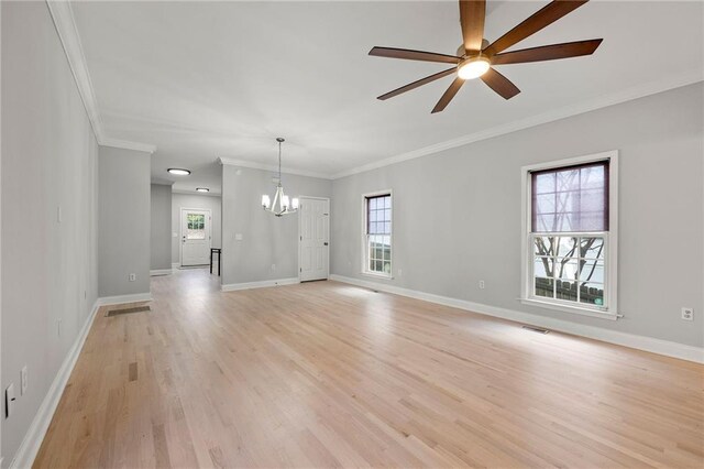 unfurnished living room featuring a healthy amount of sunlight, ceiling fan with notable chandelier, light hardwood / wood-style floors, and crown molding