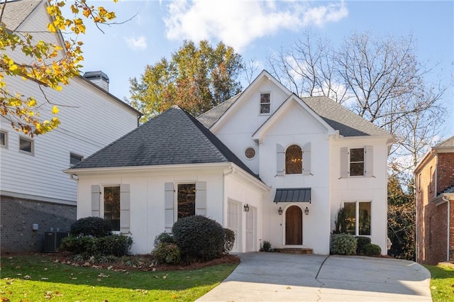 view of front of home featuring central AC unit, driveway, roof with shingles, a front lawn, and metal roof