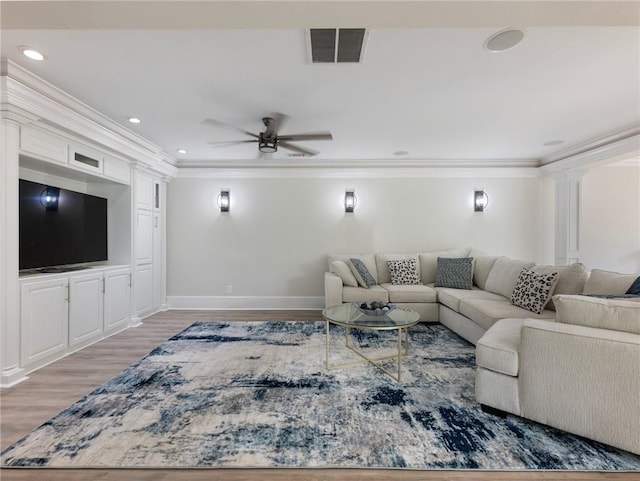 living room featuring hardwood / wood-style floors, crown molding, ceiling fan, and ornate columns