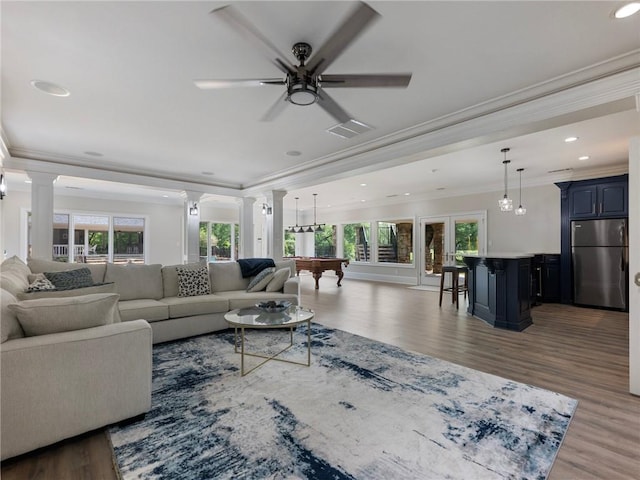 living room featuring crown molding, ceiling fan, dark hardwood / wood-style floors, and ornate columns