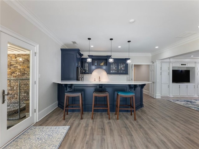 kitchen featuring stainless steel fridge, blue cabinetry, a breakfast bar, hanging light fixtures, and kitchen peninsula