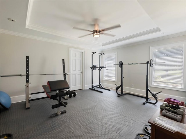 exercise area with ceiling fan, ornamental molding, and a raised ceiling