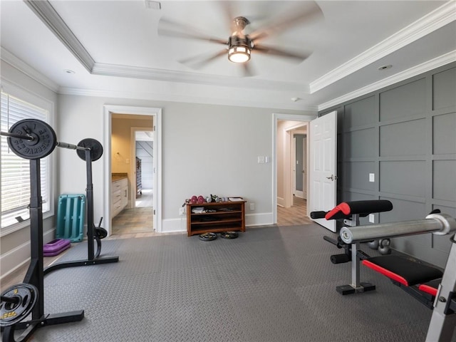 exercise area with a tray ceiling, crown molding, and ceiling fan