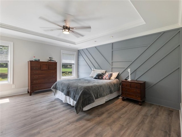 bedroom with hardwood / wood-style flooring, ornamental molding, and a raised ceiling