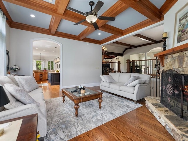 living room featuring coffered ceiling, a fireplace, beam ceiling, and light hardwood / wood-style flooring