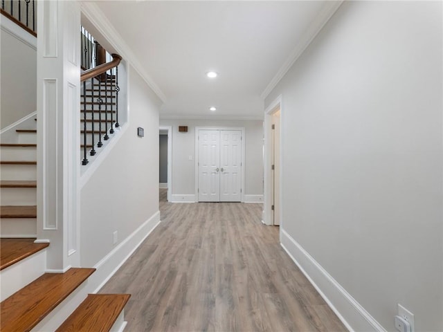 corridor with ornamental molding and light hardwood / wood-style flooring