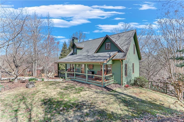 view of front of property featuring a porch, a chimney, a front lawn, and roof with shingles