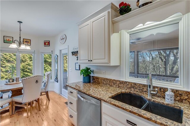 kitchen with light wood-style flooring, a sink, white cabinets, pendant lighting, and stainless steel dishwasher