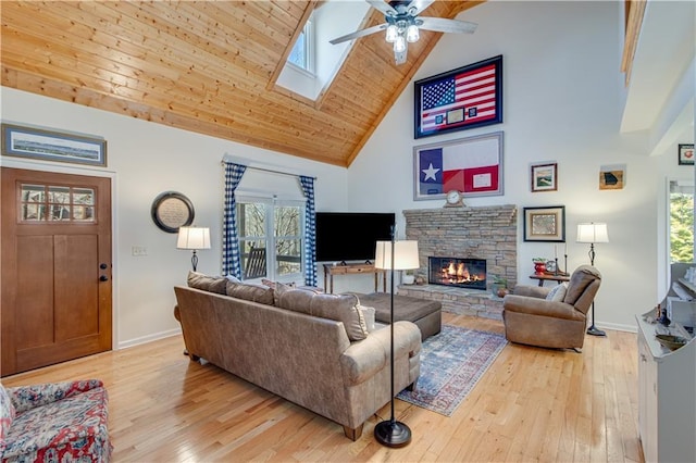 living room with baseboards, high vaulted ceiling, a stone fireplace, and light wood finished floors