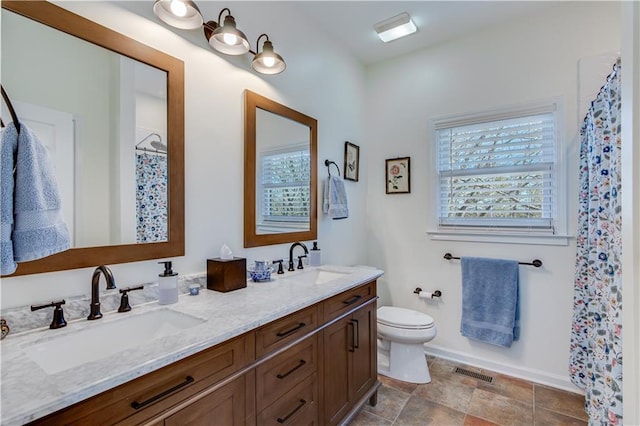 bathroom featuring double vanity, visible vents, toilet, and a sink