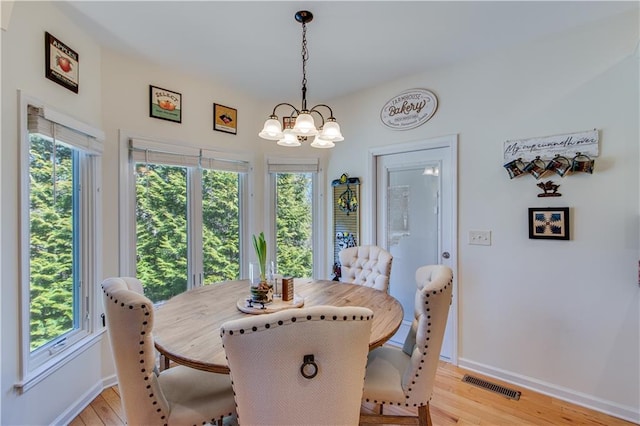 dining space featuring visible vents, baseboards, an inviting chandelier, and light wood finished floors