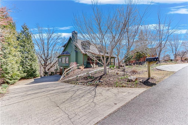 view of property exterior with aphalt driveway and a chimney