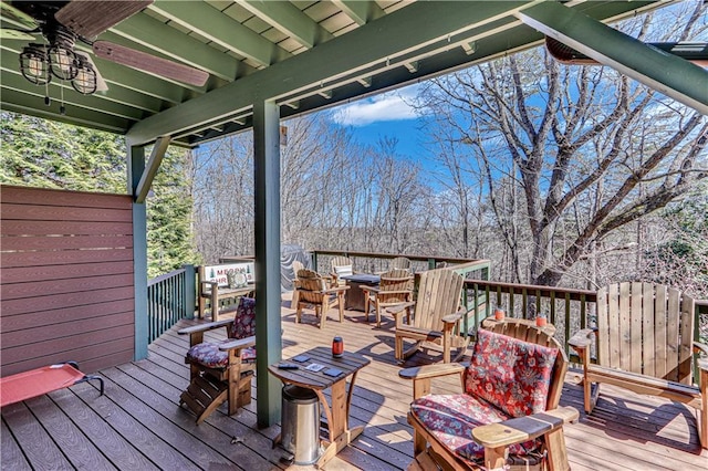 wooden terrace with outdoor dining space and ceiling fan