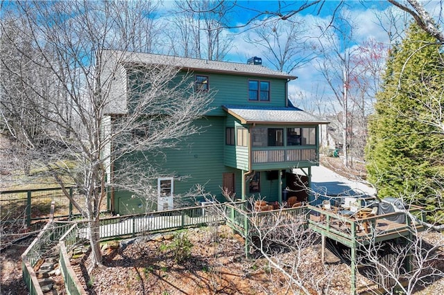 back of property with roof with shingles, fence, a sunroom, and a chimney