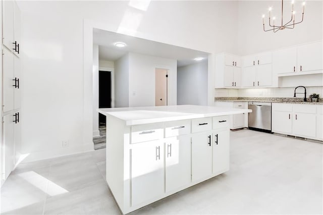 kitchen featuring white cabinetry, stainless steel dishwasher, hanging light fixtures, and sink