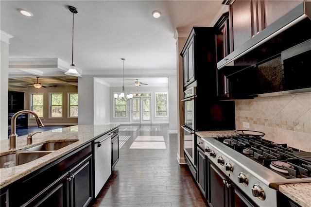 kitchen featuring sink, light stone counters, ventilation hood, appliances with stainless steel finishes, and pendant lighting