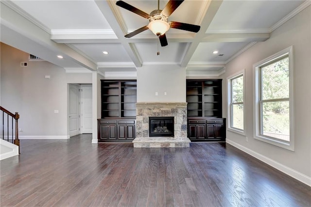 unfurnished living room with dark hardwood / wood-style flooring, beam ceiling, and a stone fireplace