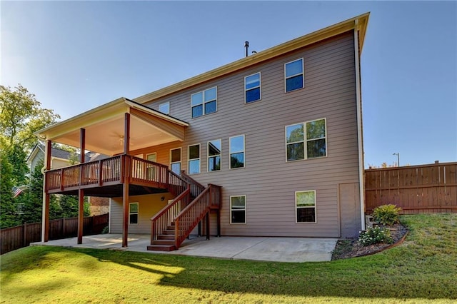 back of property featuring a wooden deck, a patio area, and a lawn